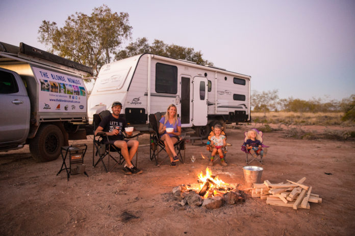 Tracy and Rob Morris and their children, in front of their caravan, by a campfire